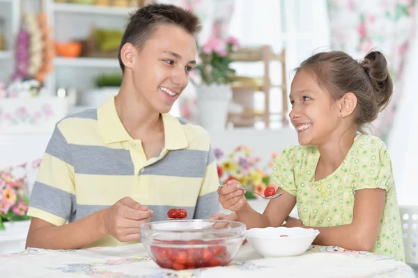 愉快的兄弟和姐妹吃新鲜的草莓在厨房 — 图库照片