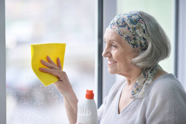 Seniorin putzt Fenster — Stockfoto