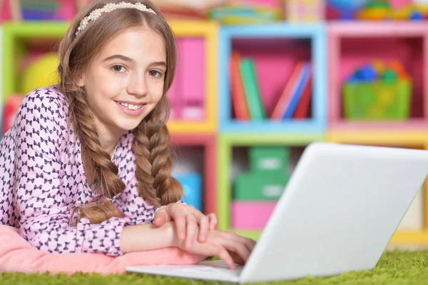 家の緑の床に横たわっている間ノート パソコンを使用して感情的なかわいい女の子 — ストック写真