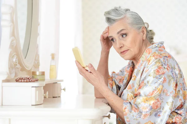 Mujer mayor aplicando maquillaje — Foto de Stock