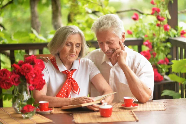 Happy Senior Par Läsning Bok Medan Dricker Kaffe Terrassen Hemma — Stockfoto