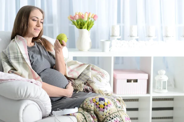 美丽的孕妇坐在扶手椅与苹果 — 图库照片