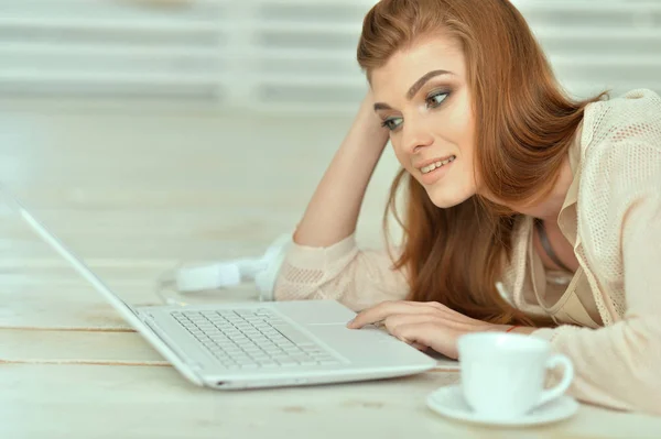 Genç kadın laptop ile yerde yatarken — Stok fotoğraf