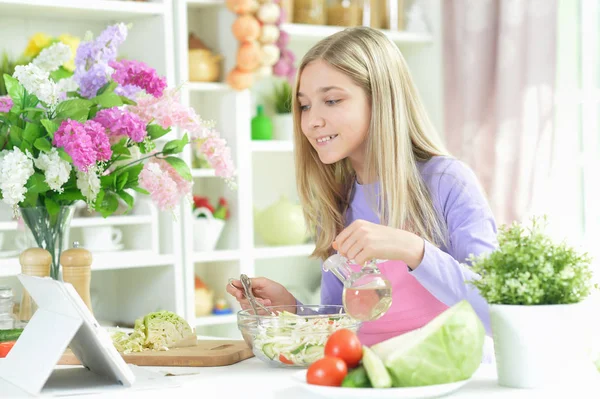 Roztomilá Dívka Připravuje Čerstvý Salát Kuchyňském Stole Tabletu Doma — Stock fotografie