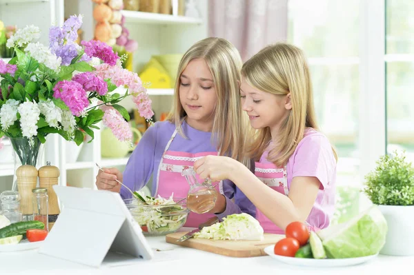 Two Girls Pink Aprons Preparing Salad Kitchen Table Tablet — Stock Photo, Image