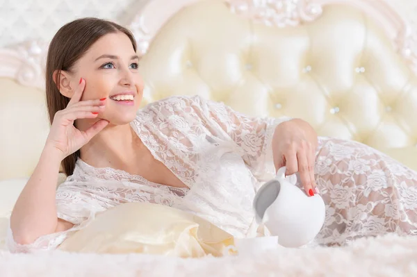 Vacker Ung Kvinna Dricker Kaffe Medan Liggande Mjuk Beige Säng — Stockfoto