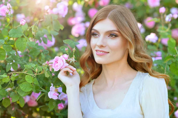 美丽的年轻女子冒充玫瑰树丛 — 图库照片