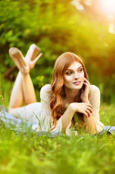 緑の草原の上に横たわる美しい若い女性 — ストック写真