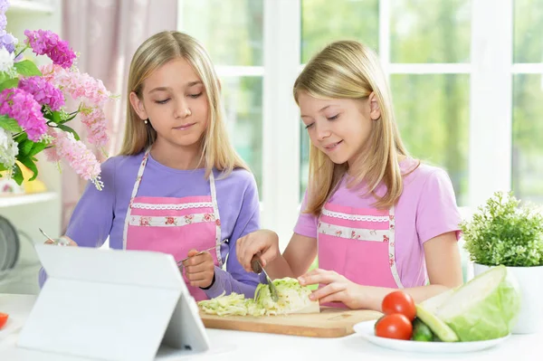 Zwei Mädchen Rosa Schürzen Bereiten Salat Auf Küchentisch Mit Tablet — Stockfoto