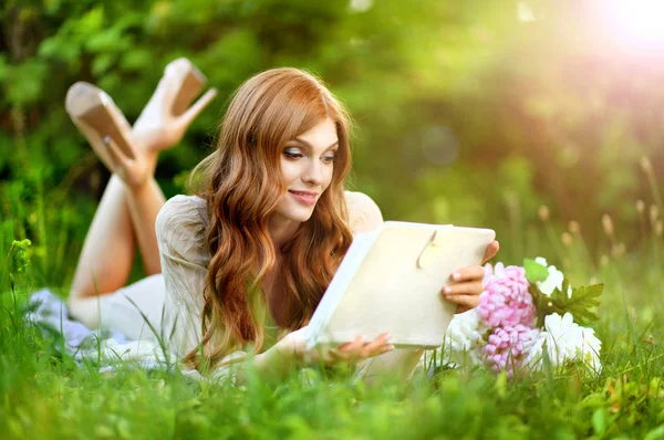 緑の草原に横たわり タブレットを使用して美しい若い女性 — ストック写真
