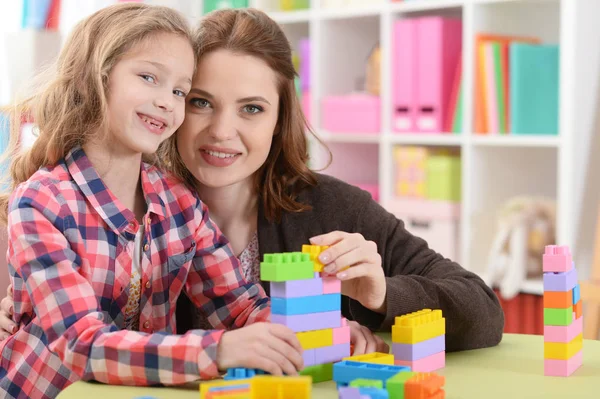 かわいい女の子と彼女の母親が彼女の部屋でカラフルなプラスチック製のブロックを一緒に遊んで — ストック写真