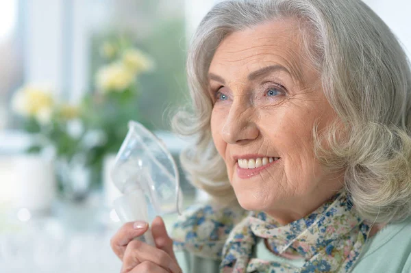 吸入器とキッチンで座って病気の年配の女性の肖像画 — ストック写真