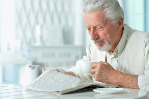 Emotional senior man  reading newspaper at home