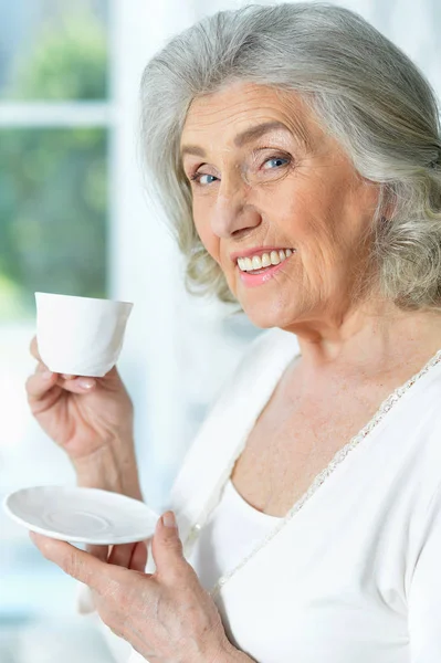 自宅でお茶を飲む美しい笑顔の先輩女性 — ストック写真