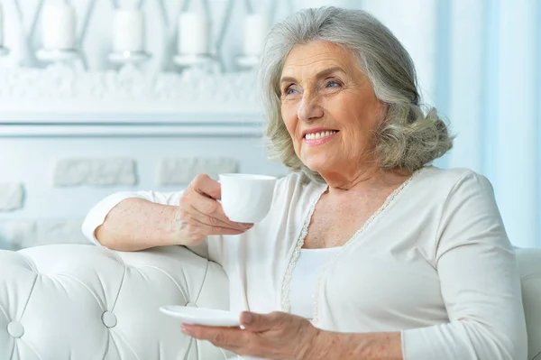 美丽的微笑高级女人在家里喝茶 — 图库照片