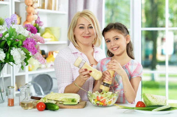 可爱的小女孩和她的妈妈一起在厨房桌子边做饭 — 图库照片