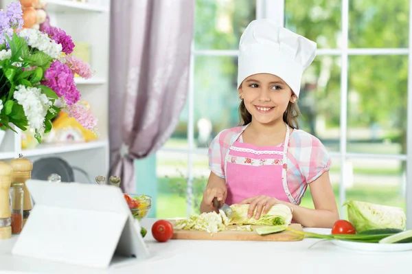 Schattig Klein Meisje Voorbereiding Van Frisse Salade Keukentafel Met Tablet — Stockfoto