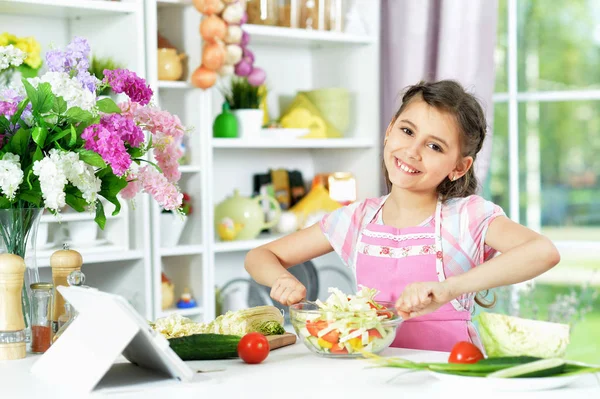 Sevimli Küçük Kız Mutfak Masasında Evde Tablet Ile Taze Salata — Stok fotoğraf