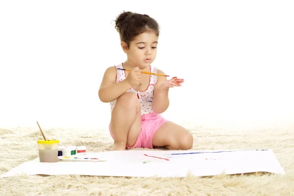 可爱的女孩画油漆在地板上的白色背景 — 图库照片