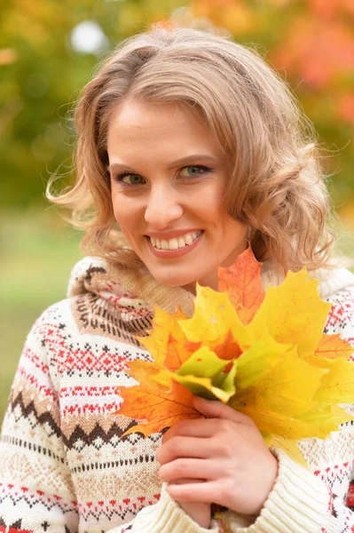 公園で紅葉を保持している美しい若い女性 — ストック写真
