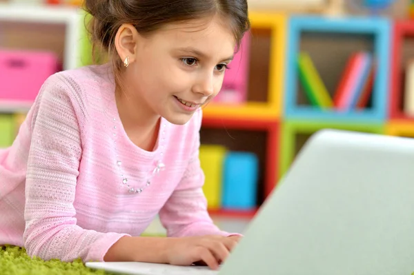 情感可爱的女孩使用笔记本电脑 而躺在地板上与绿色地毯在家里 — 图库照片