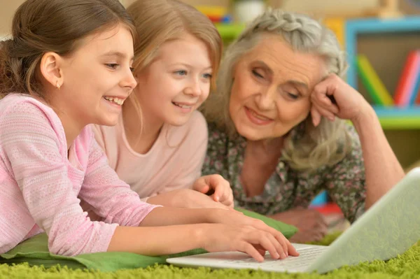 Senior Vrouw Met Kleindochters Laptop Kijken Terwijl Liggend Vloer — Stockfoto