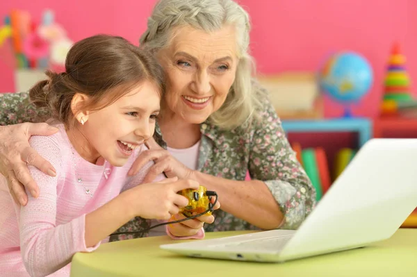自宅のラップトップのコンピューター ゲームをプレイして彼女の孫娘とおばあちゃん — ストック写真