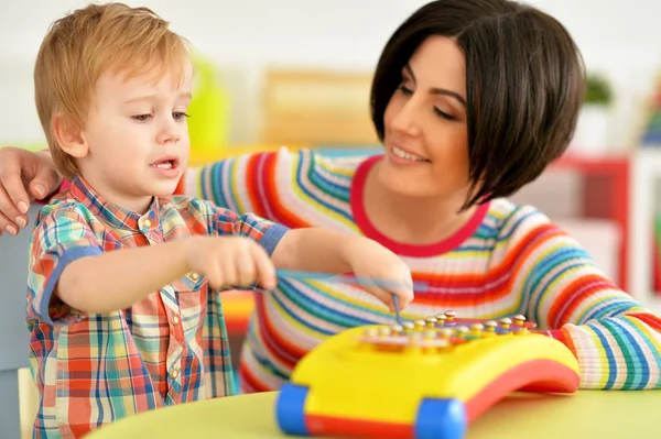 若い母親とかわいい息子音楽おもちゃで遊んで — ストック写真