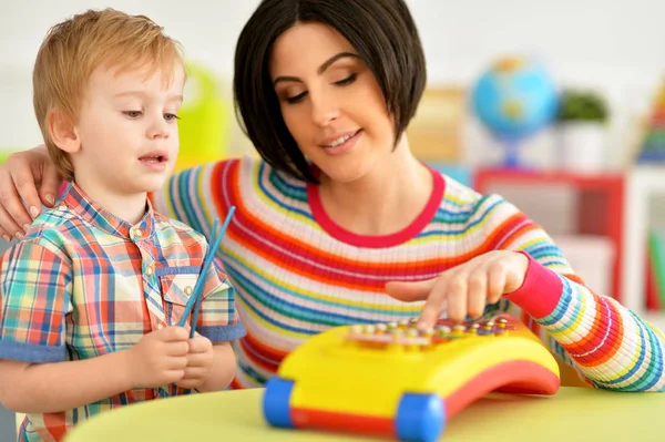 若い母親とかわいい息子音楽おもちゃで遊んで — ストック写真