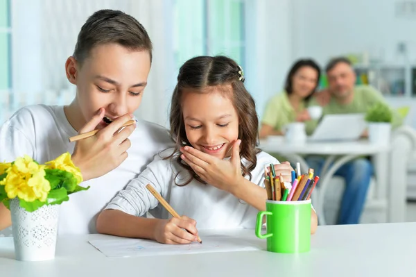 Lächelndes Geschwisterpaar Zeichnet Mit Buntstiften Gemeinsam Drinnen — Stockfoto