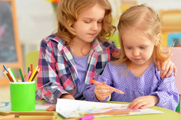 可爱的小女孩坐在桌旁 用铅笔在他们的房间中绘图 — 图库照片