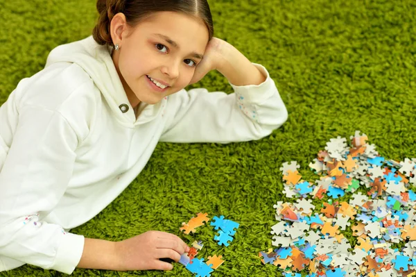 Schattig Klein Meisje Verzamelen Van Puzzelstukken Liggend Het Groene Tapijt — Stockfoto