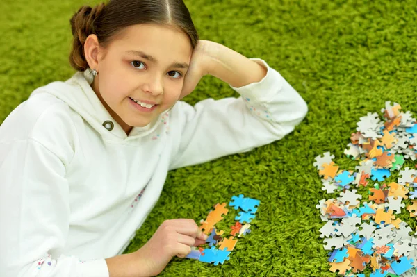 Schattig Klein Meisje Verzamelen Van Puzzelstukken Liggend Het Groene Tapijt — Stockfoto