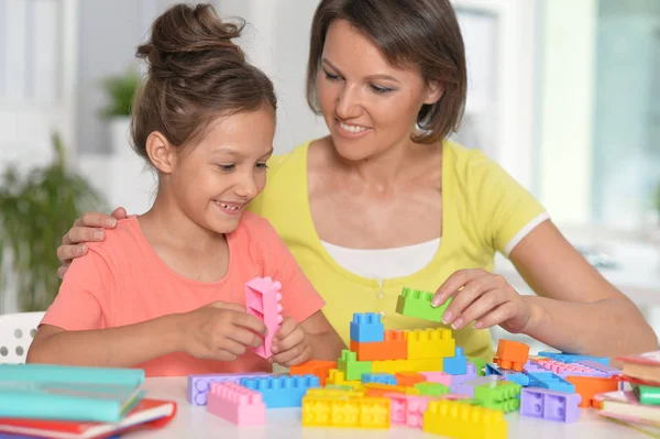 小女孩和她的母亲在家里玩五颜六色的塑料块 — 图库照片