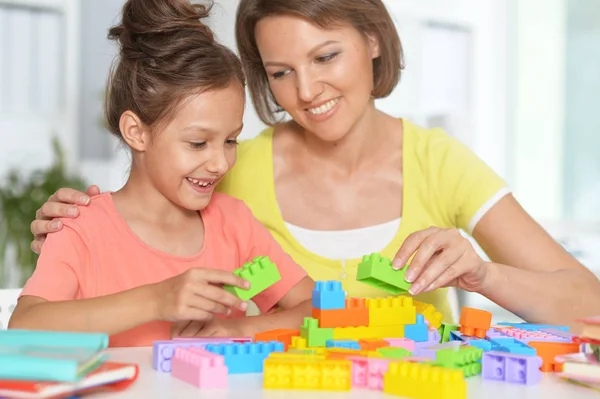 小さな女の子と彼女の母親を自宅にカラフルなプラスチック製のブロックで遊んで — ストック写真