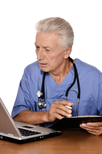 白い背景の上のノート パソコンで高齢の医者 — ストック写真