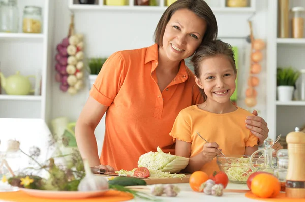 可愛いです女の子とともに彼女のお母さん料理とともにキッチンテーブル — ストック写真