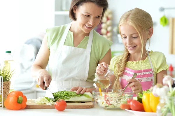 可爱的小女孩和她的妈妈一起在厨房桌子边做饭 — 图库照片