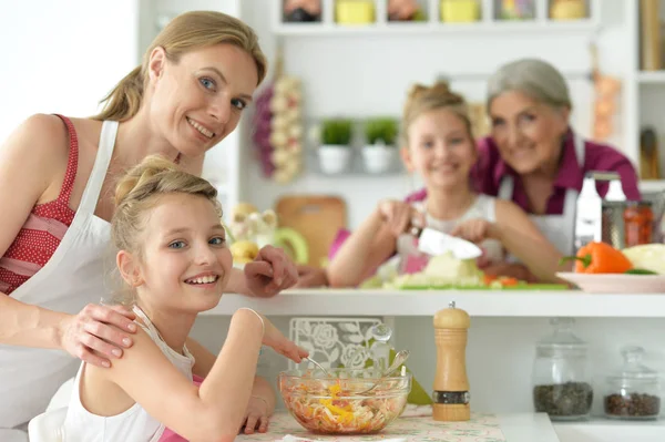 可愛いです女の子とともにお母さん調理おいしい新鮮なサラダでキッチン — ストック写真