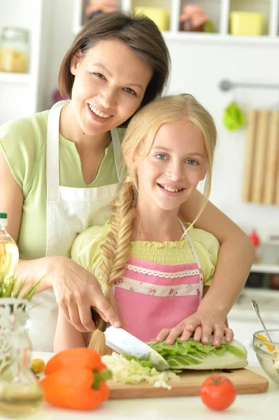 可愛いです女の子とともに彼女のお母さん料理とともにキッチンテーブル — ストック写真