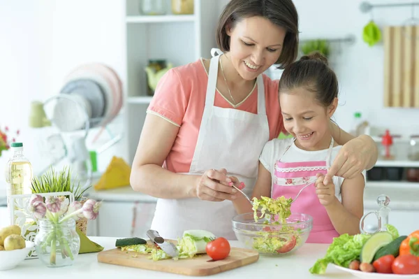 可愛いです女の子とともに彼女のお母さん料理とともにキッチンテーブル — ストック写真