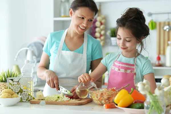 可爱的小女孩和她的妈妈一起在厨房桌子边做饭 — 图库照片