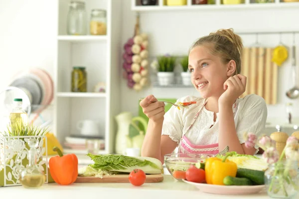 かわいい女の子は台所でサラダを食べる — ストック写真