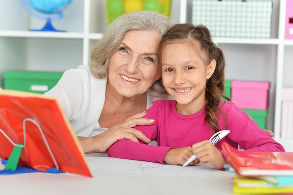 祖母と孫娘が一緒に宿題をする姿 — ストック写真