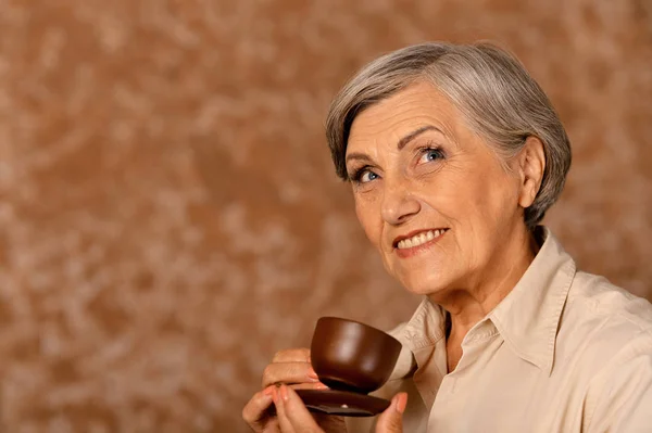 自宅でお茶を飲む美しい笑顔の先輩女性 — ストック写真
