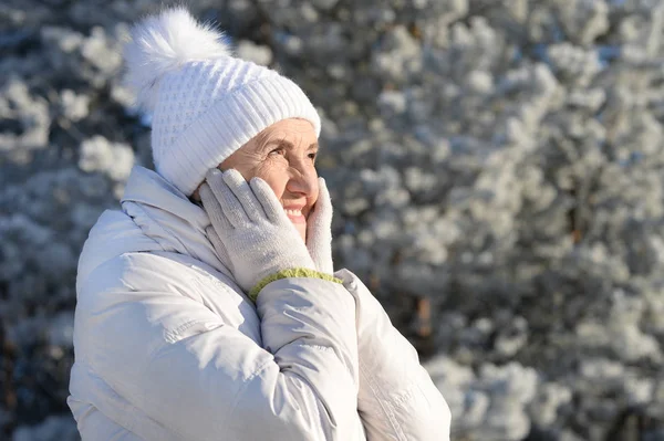 站在雪地的冬日公园里 头戴一顶暖和的帽子 快乐而美丽的老妇人 — 图库照片