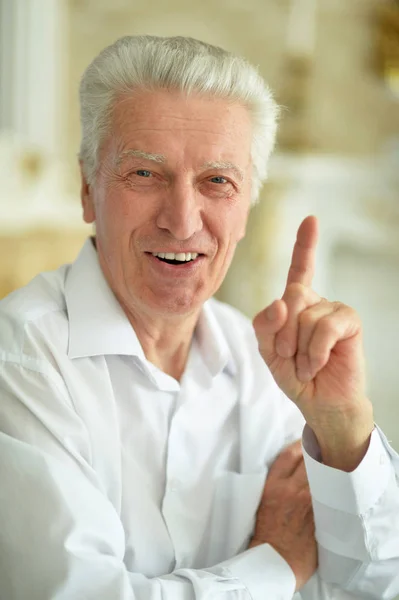 Portrét Usměvavého Staršího Muže Ukazujícího Prstem Doma — Stock fotografie