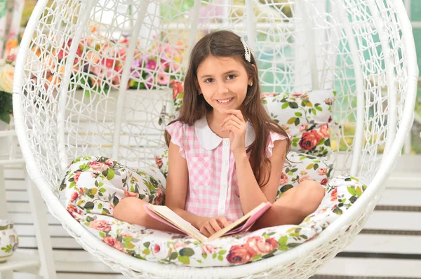 快乐的小女孩在看秋千上的书 — 图库照片