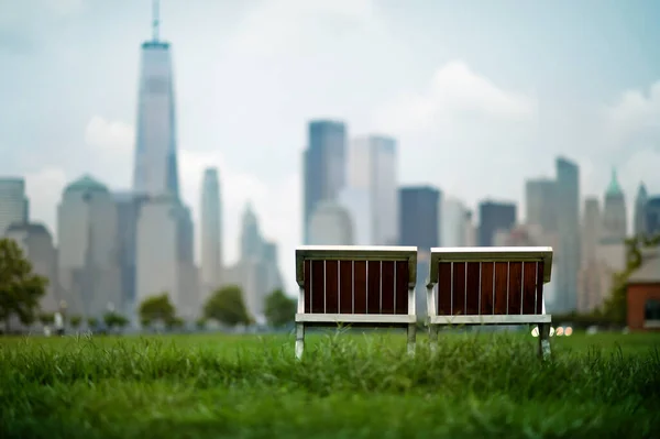 绿地上的空木椅 背景是现代城市景观 — 图库照片