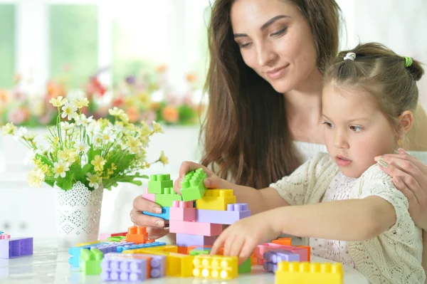 小さな娘と幸せな母親は家でカラフルなプラスチックブロックで遊んでいます — ストック写真